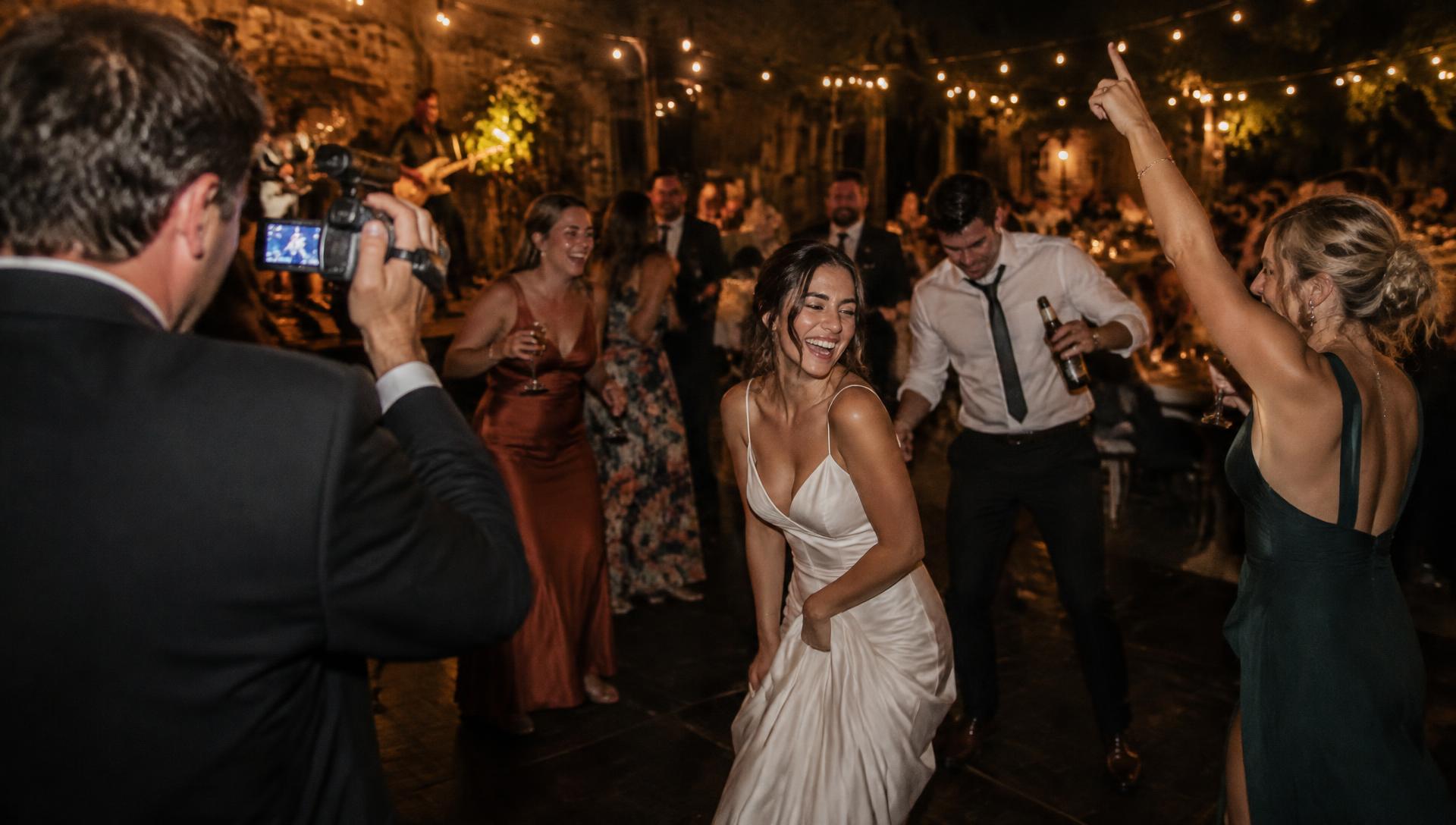 Guests dancing at a wedding while a friend films